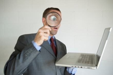 Agent looking at computer with magnifying glass